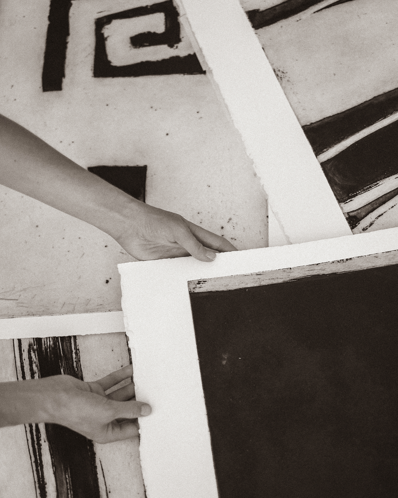 Hands arranging large monochrome art prints on paper.